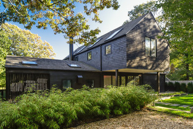 Large transitional black two-story wood exterior home photo in New York with a shingle roof