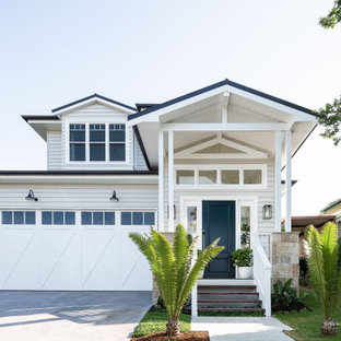 This is an example of a large beach style two-storey grey house exterior in Sydney with a gable roof, a metal roof and a black roof.
