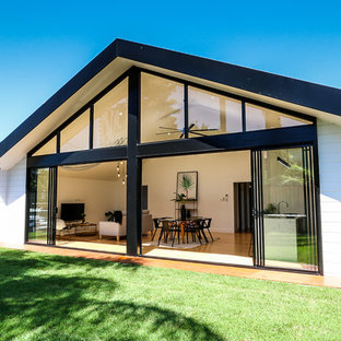 Photo of a large contemporary one-storey white house exterior in Brisbane with wood siding and a gable roof.