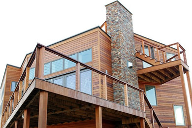 Esempio della facciata di una casa grande beige contemporanea a due piani con rivestimento in legno e tetto a capanna