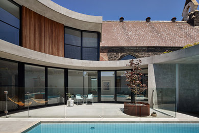 Diseño de fachada de casa gris contemporánea grande de dos plantas con revestimiento de hormigón, tejado plano y tejado de metal