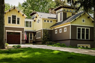 Diseño de fachada de casa amarilla de estilo americano grande de dos plantas con revestimiento de madera, tejado a dos aguas y tejado de metal