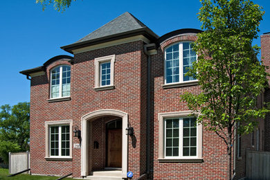 Mid-sized elegant red two-story brick house exterior photo in Chicago with a hip roof and a shingle roof