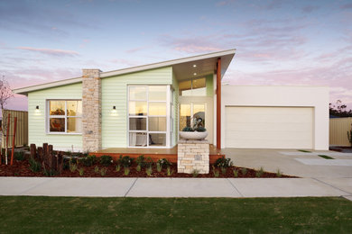 Cette photo montre une façade de maison verte bord de mer en bois de taille moyenne et de plain-pied avec un toit en métal.
