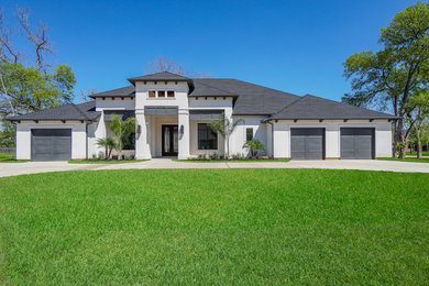 Large transitional white one-story stucco house exterior idea in Houston with a hip roof and a shingle roof