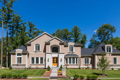 Example of a huge classic beige three-story stucco exterior home design in Boston with a hip roof