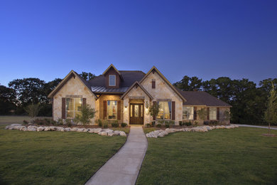 Mid-sized traditional beige two-story stone house exterior idea in Houston with a hip roof and a shingle roof