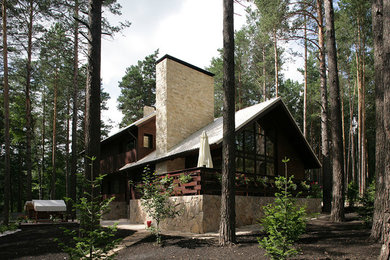 Medium sized and brown rustic house exterior in Novosibirsk with three floors, wood cladding and a pitched roof.