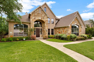 Large trendy beige two-story stone house exterior photo in Austin with a shingle roof
