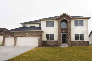 Large traditional beige two-story vinyl exterior home idea in Chicago with a hip roof