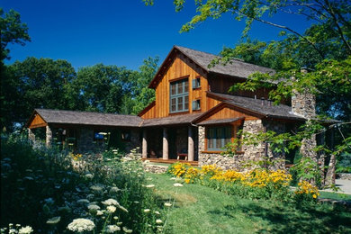 This is an example of an expansive rustic two floor house exterior in New York with wood cladding.