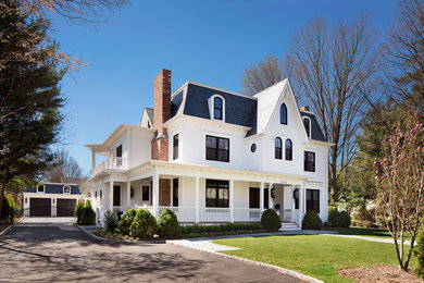 Стильный дизайн: большой, трехэтажный, белый частный загородный дом в викторианском стиле с облицовкой из винила и крышей из гибкой черепицы - последний тренд