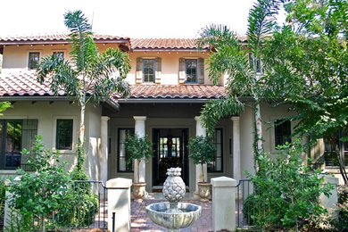Imagen de fachada de casa beige mediterránea de tamaño medio de dos plantas con revestimiento de estuco, tejado a cuatro aguas y tejado de teja de barro