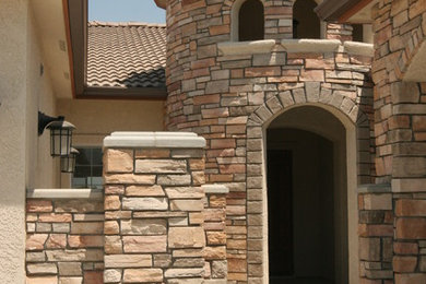 Inspiration for a large mediterranean beige one-story stone exterior home remodel in Other with a hip roof