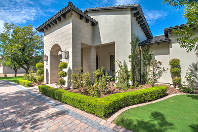 Inspiration for a large mediterranean beige two-story stucco exterior home remodel in Phoenix with a tile roof