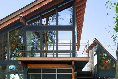 Modelo de fachada de casa gris actual de tamaño medio de dos plantas con revestimiento de madera, tejado de un solo tendido y tejado de metal