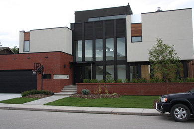 Example of a mid-sized minimalist beige three-story brick flat roof design in Calgary