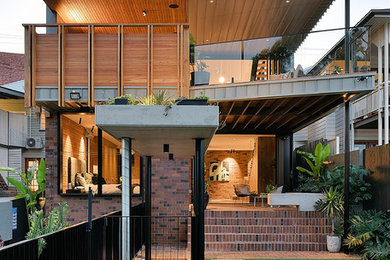 Ejemplo de fachada de casa contemporánea grande de tres plantas con revestimiento de ladrillo y tejado de metal