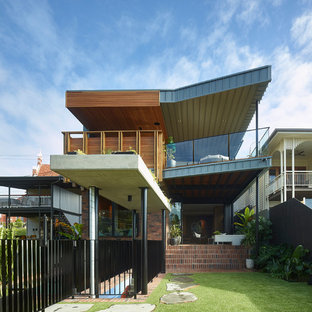 This is an example of a contemporary two-storey grey house exterior in Brisbane with mixed siding and a flat roof.