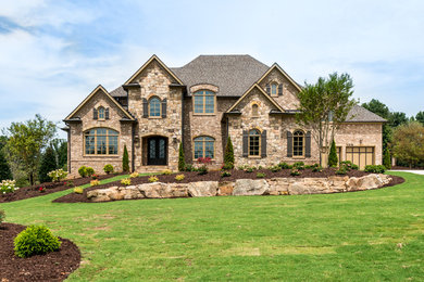 This is an example of a large and beige classic two floor house exterior in Atlanta with stone cladding and a half-hip roof.