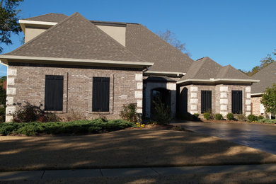 Example of a large classic brown one-story brick exterior home design in Other with a hip roof