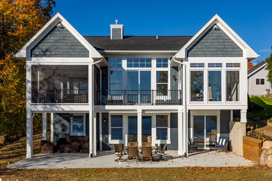 Diseño de fachada de casa azul marinera grande de dos plantas con tejado de teja de madera, revestimientos combinados y tejado a dos aguas