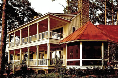 Idée de décoration pour une grande façade de maison jaune tradition en bois à un étage avec un toit à deux pans.