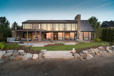 Beach style brown two-story stone house exterior photo in Toronto with a hip roof and a shingle roof