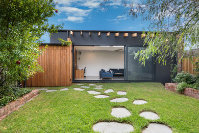 Small and black contemporary bungalow render detached house in Melbourne with a flat roof and a metal roof.