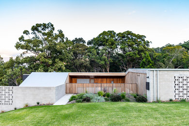 Modelo de fachada de casa gris minimalista a niveles con revestimiento de hormigón, tejado plano y tejado de metal