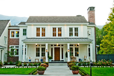 Imagen de fachada de casa blanca tradicional grande de dos plantas con revestimiento de ladrillo, tejado a dos aguas y tejado de varios materiales