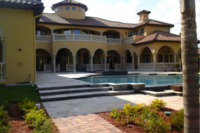 Large mediterranean yellow two-story stucco house exterior idea in Orlando with a hip roof and a tile roof