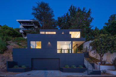 Diseño de fachada de casa negra moderna de tamaño medio de tres plantas con revestimiento de aglomerado de cemento, tejado plano y techo verde