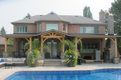 Large and red classic two floor brick house exterior in Toronto with a half-hip roof.