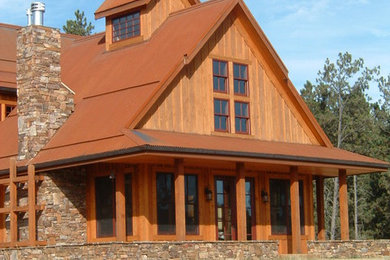 Immagine della facciata di una casa grande marrone rustica a due piani con rivestimento in legno