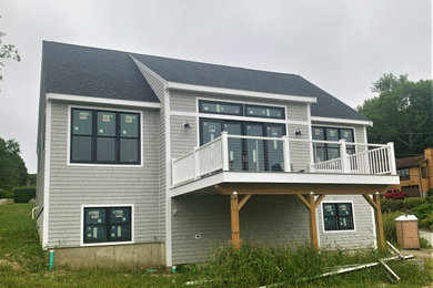 Modelo de fachada de casa gris moderna de tamaño medio de dos plantas con revestimiento de madera, tejado de un solo tendido y tejado de teja de madera