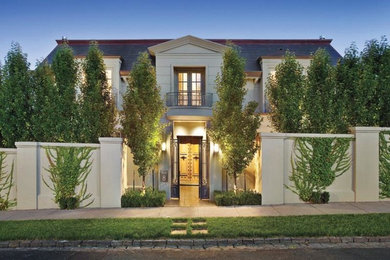 Imagen de fachada de casa beige clásica grande de dos plantas con revestimiento de estuco y tejado de teja de barro