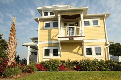 Modelo de fachada amarilla costera de tres plantas con revestimiento de aglomerado de cemento