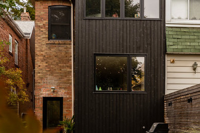 Modelo de fachada negra contemporánea de dos plantas con revestimiento de madera y tejado de teja de madera