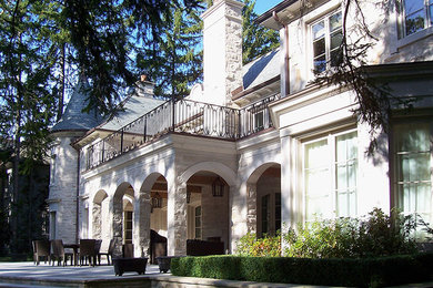 Imagen de fachada de casa beige clásica grande de dos plantas con revestimiento de piedra, tejado a cuatro aguas y tejado de teja de madera