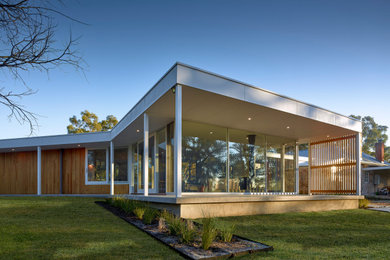 Ejemplo de fachada de casa actual de una planta con revestimiento de madera, tejado plano y tejado de metal