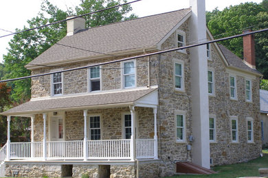 Example of a large country beige two-story stone gable roof design in Philadelphia