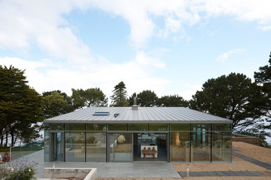 Idées déco pour une façade de maison contemporaine en verre de taille moyenne et de plain-pied avec un toit plat.