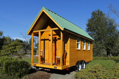 Cette image montre une petite façade de maison marron traditionnelle en bois à un étage avec un toit à deux pans.
