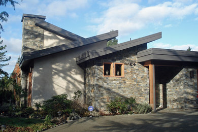 Example of a mid-sized trendy beige two-story stone house exterior design in Vancouver with a metal roof