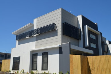 Imagen de fachada de casa pareada gris actual de tamaño medio de dos plantas con revestimientos combinados y tejado plano