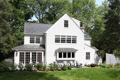 Modelo de fachada de casa blanca clásica grande de tres plantas con revestimiento de madera, tejado a dos aguas y tejado de teja de barro