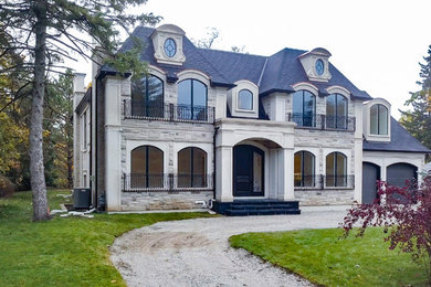 Inspiration for a large timeless white two-story stone house exterior remodel in Toronto with a shingle roof