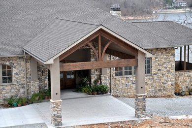 Cette photo montre une façade de maison beige chic en pierre de taille moyenne et de plain-pied avec un toit à quatre pans et un toit en shingle.