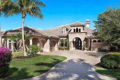 Large tuscan beige one-story stucco gable roof photo in Miami
